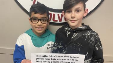 Two middle school students holding paper, smiling.