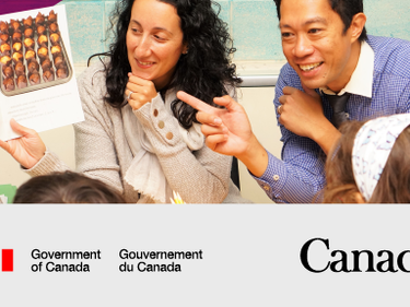 Female holding a book and a male pointing at the book