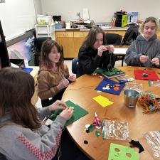 Four female students at a table doing a craft